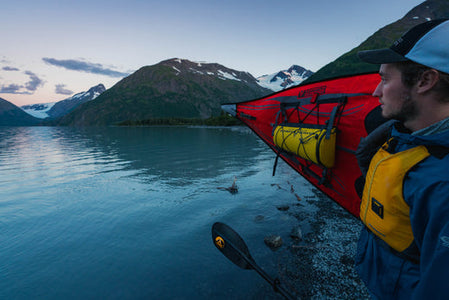 person holding a kayak and looking out over the water