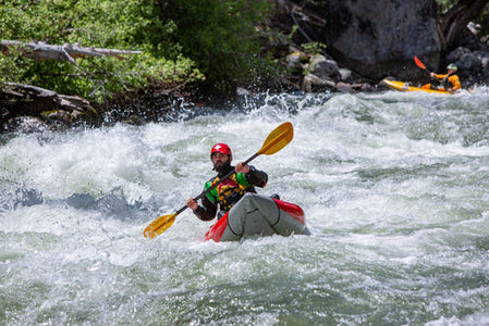 man paddling a kayak on a rushing river