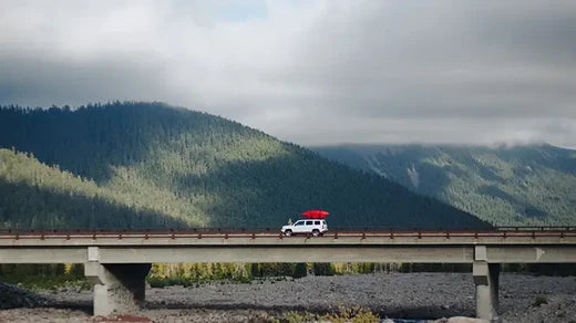 Canoe on the top of a car driving over a bridge