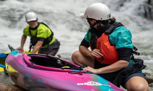 Kayakers in paddling shirts helmets and lifejackets on the beach