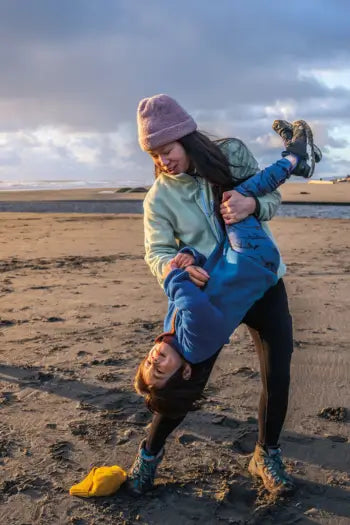 woman holding child on the beach wearing Patagonia fleece