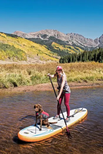 woman stand up paddle boarding with her dog