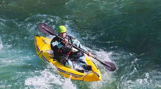 man wearing helmet paddling an inflatable kayak