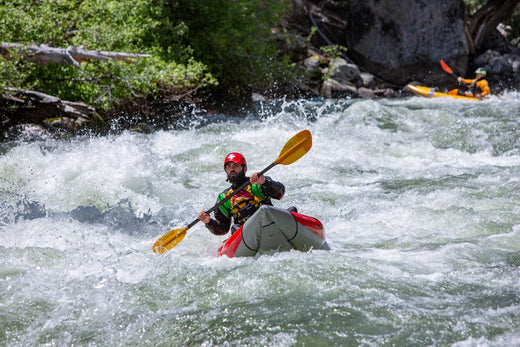 man paddling a kayak on a rushing river