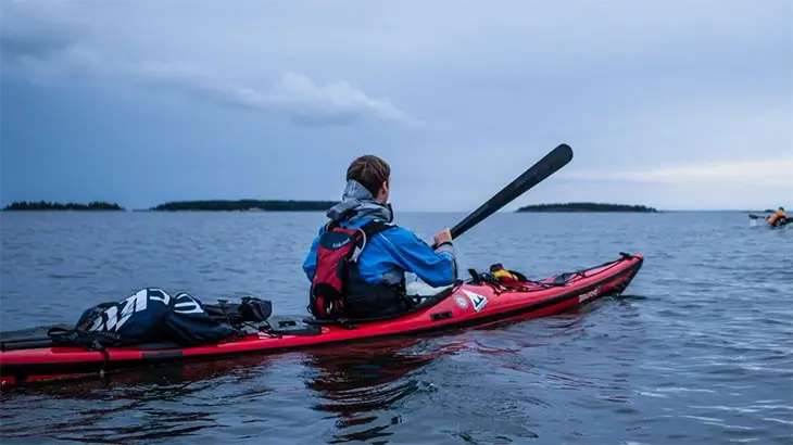 Man kayaking on lake in dry suit