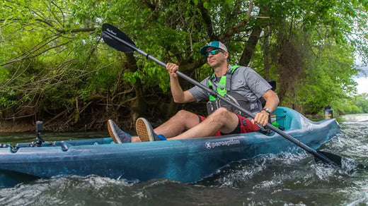 Ken Whiting paddling a kayak under a tree