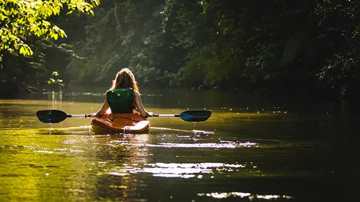 woman floating in kayak on calm green water