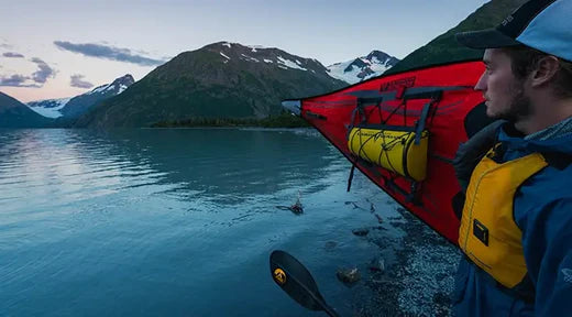 man holding a kayak looking out over the water