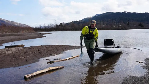 Ken Whiting pulling a kayak out of the water onto a beach