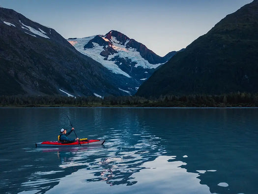 man kayaking on serene mountain lake