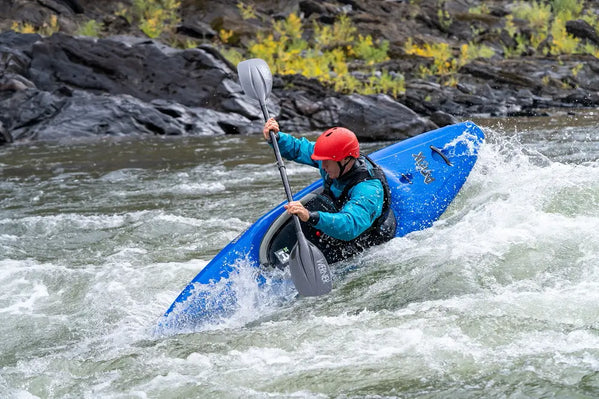 kayaker paddling through whitewater rapids in a kayak
