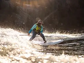 Man stand-up paddle boarding on a river