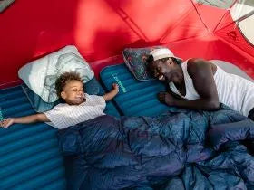 father and child camping in sleeping bags