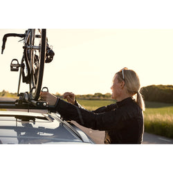 Thule FastRide Bike Roof Rack in Black close up of bike rider unstrapping wheel from rack