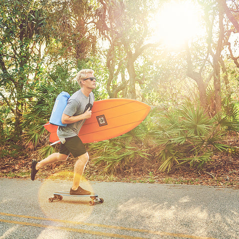 Man on a skateboard with an IceMule Classic Cooler over his shoulder