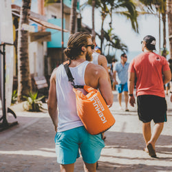 Man walking down a street with an IceMule Classic Cooler over his shoulder